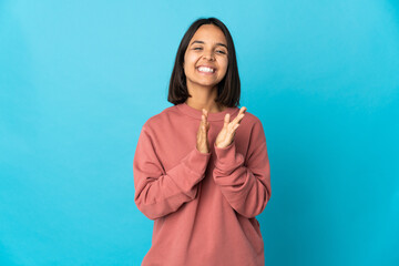 Young latin woman isolated on blue background applauding after presentation in a conference