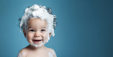 Little smiling baby boy with big soap foam on her head in her hair on a blue background. Copy space - obrazy, fototapety, plakaty