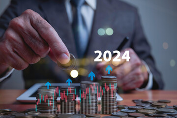 Businessman holds coins and graph to analyze currency values ​​in 2024. It is a concept of...