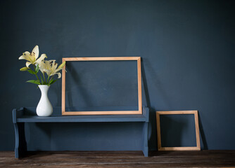 flowers in vase and wooden frame on background dark wall