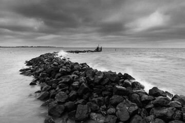 Stone seawalls in Markermeer (Netherlands) withstand the storm. A cloudy start of the day with strong winds and threatening clouds in West-Friesland.