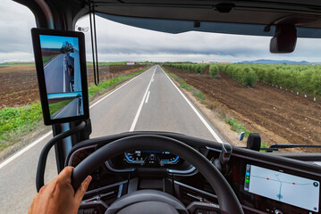 View from the driver's position of a truck of a road in the middle of crop fields and the driver...