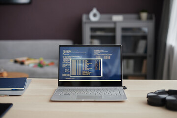 Background image of open laptop with code lines on screen at home office workplace in lived...