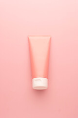 Blank pink squeeze bottle plastic tube on pink background. Packaging of cream, lotion, gel, facial...