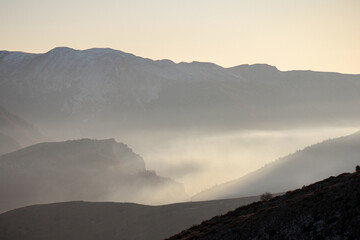 Mountainous expanse cloaked in mist.