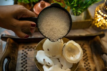 Sugar and coconut in a wooden plate, Coconut in brass bowl and sugar pouring by women, Coconut...