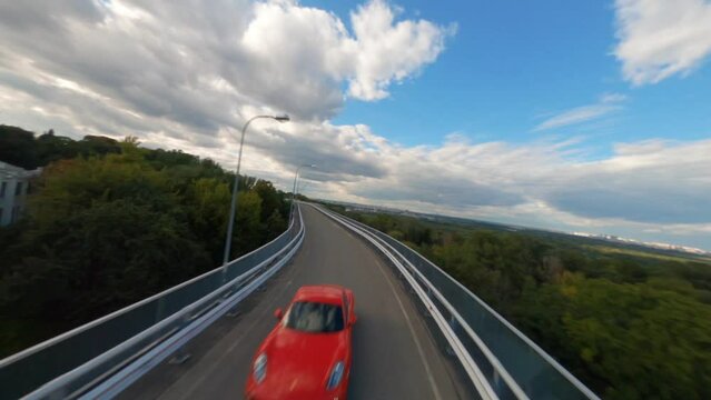 FPV shot of a Ferrari following behind a Lamborghini down a winding country road, Aerial red and yellow sports car, Enjoying scenic car ride on a sunny day, Sports car driving at a motor racing track