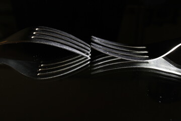 Tenedores de acero de cuatro puntas como utensilios de comida, reflejados en la superficie ...