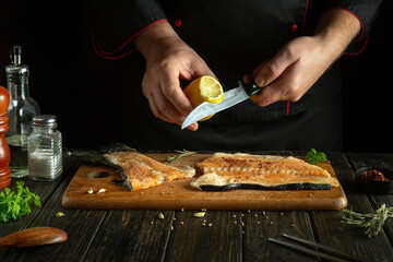 Experienced chef seasoning trout steak with fresh lemon on the kitchen table. Pink salmon is a delicious breakfast fish. The process of preparing fish in the hotel kitchen.