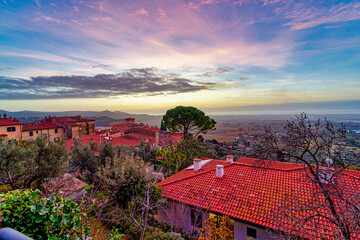 City landscape at sunset from the belvedere square of Castagneto Carducci in the background the sea and the Tuscan Italy countryside - obrazy, fototapety, plakaty