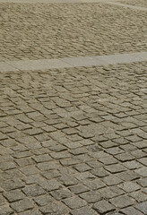 The texture of the paving slab (paving stones) of many small stones of a square shape under bright sunlight