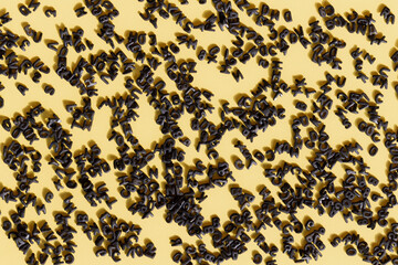 Yellow background with a multitude of black letters spread over the surface with direct light that generates shadows of the letters
