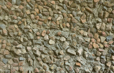 The texture of a strong stone wall of many concreted stones of various shapes
