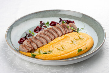 Duck breast, with pumpkin puree, cherry sauce and peanuts. Isolated image