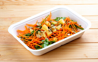Carrot salad with orange. Healthly food. Takeaway food. On a wooden background.