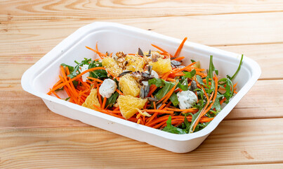 Carrot salad with orange. Healthly food. Takeaway food. On a wooden background.