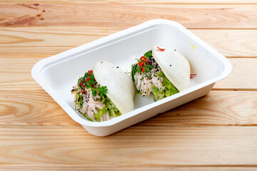 Steamed rice buns "Bao" with chicken. Healthy food. Takeaway food. On a wooden background.
