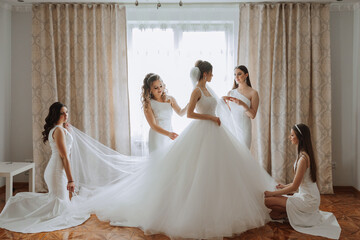 Friends rejoice with the bride in the morning. They take pictures, smile, help the bride fasten her...