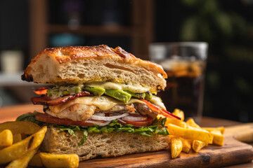 Grilled chicken breast sandwich with lettuce, tomato, bacon, red onion rings and avocado served on...