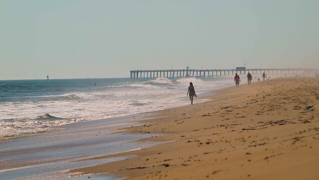 Woman walking along the beach in Ocean City MD.  A female is enjoying the last warmth of an October heatwave.