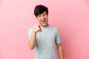 Young Russian man isolated on pink background surprised and pointing front