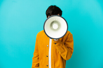 Young Russian man isolated on blue background shouting through a megaphone to announce something
