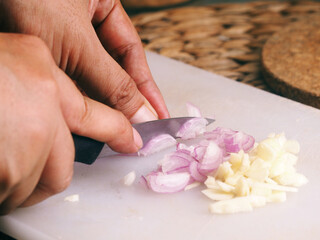 Obraz na płótnie Canvas hand with kitchen knife, cutting onion and red onion in white cutting board