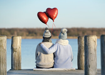 frisch verliebtes Paar am See mit roten Herzballons