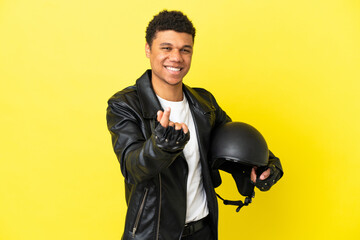 Young African American man with a motorcycle helmet isolated on yellow background making money gesture