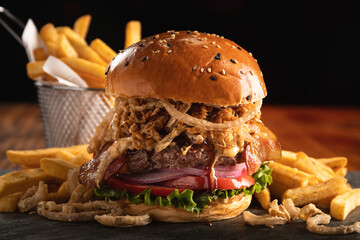 Burger with cheese, tomato, lettuce, bacon and fried onion rings, with aioli sauce and a portion of fries - obrazy, fototapety, plakaty