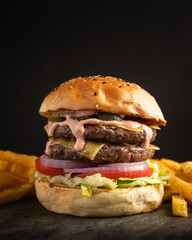 Double hamburger sandwich with cheese, lettuce, tomato and onion served with a portion of fries.