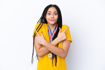 Teenager girl with braids and medals over isolated pink background pointing to the laterals having doubts