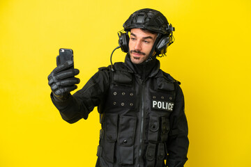 SWAT caucasian man isolated on yellow background making a selfie