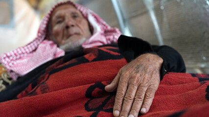 A crippled elderly man lives in a dilapidated tent. Displaced people in northwestern Syria suffer...