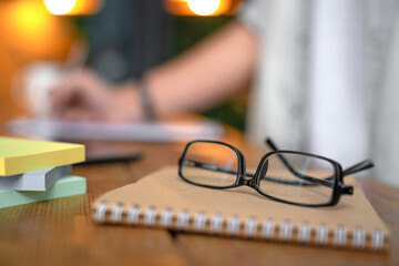 Focused photo of glasses and notebook, man taking notes, doing paperwork, writing on clipboard. New...