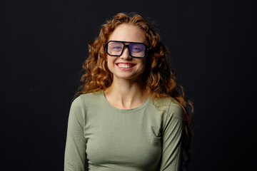 Happy smiling curly young woman wearing glasses looking at camera with joyful smile