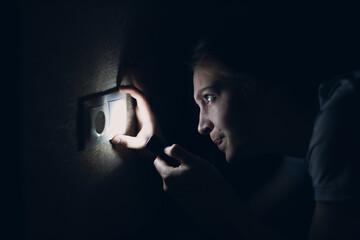 Woman young holding hand flashlight in darkness. Disconnecting home electricity and changing...