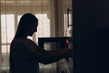 A housewife woman cooks food and looks into the oven in the kitchen.