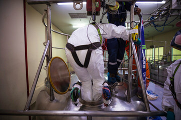 Top view male climbs up the stairs into the tank stainless chemical area confined space