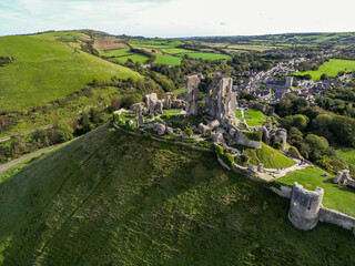 Aerial shot ruins of Corfe Castle on hill with scenery passing in the background on autumn day. Top...