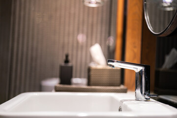 Close-up at the chrome modern designed water faucet and white bath sink at luxury toilet place....