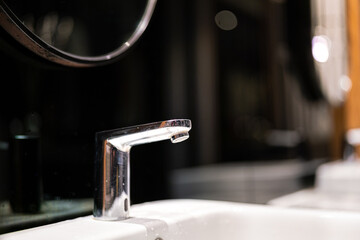 Close-up at the chrome modern designed water faucet and white bath sink at luxury toilet place....