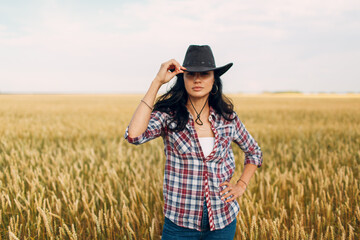 Woman american farmer wearing cowboy hat, plaid shirt and jeans at wheat field.