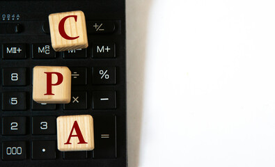 CPA - acronym on wooden cubes against the background of a calculator. Copy space