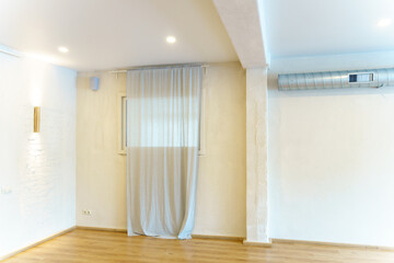 A spacious empty hall with columns and large windows. A gym with wooden floors for yoga and fitness classes. Interior design of the fitness center. A large room without furniture.