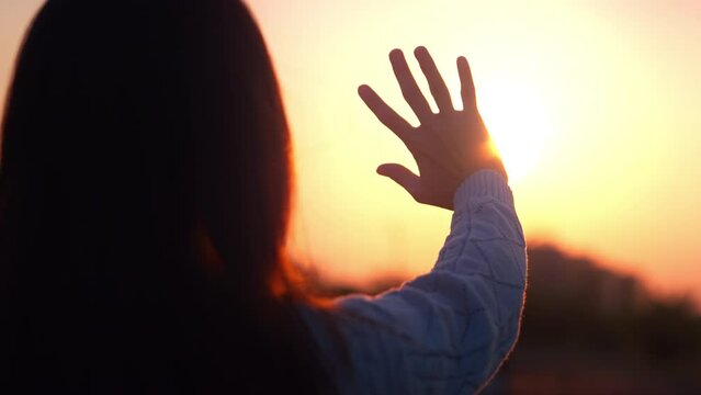Silhouette of a happy dreaming girl pulls her hand to the sunset golden hour, Hand of female touch the first sunrise on New Year.