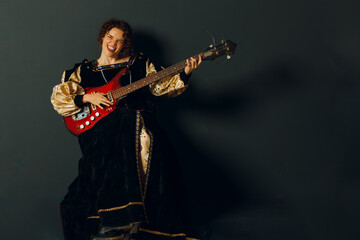 Fototapeta premium Portrait of a young adult woman playing rock music on electric guitar and dressed in a medieval dress