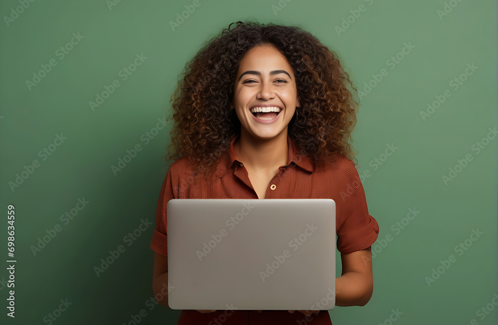 Wall mural young happy latin woman winner holding a laptop isolated on a green background. excited euphoric fem