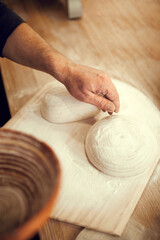 Person making dough on wooden cutting board. white and well-floured pastry. Hand gently pressing down on dough, and fingers spread out. concept of nature, food, diet, cooking, bakery.