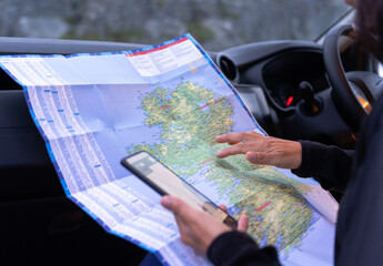Close up of woman hands checking a map and mobile phone to know the exact location of where she is...